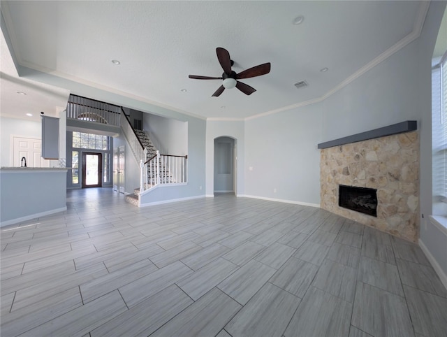 unfurnished living room featuring ceiling fan, a fireplace, and crown molding