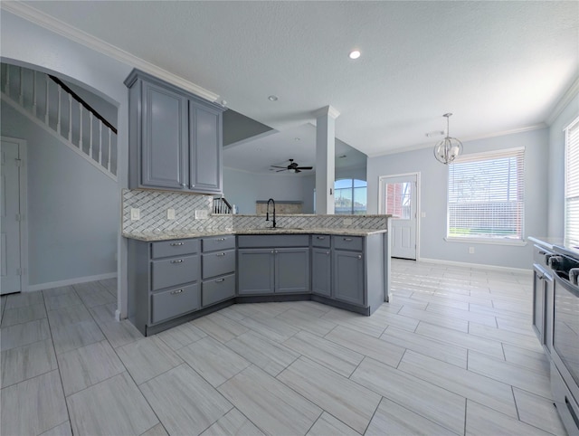 kitchen with light stone countertops, ceiling fan with notable chandelier, gray cabinetry, and sink