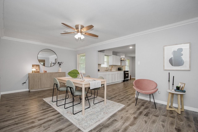 dining area featuring dark wood-type flooring, ceiling fan, crown molding, and sink