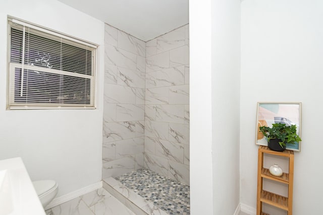 bathroom featuring tiled shower and toilet