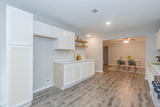 kitchen with ceiling fan, sink, white cabinets, and light wood-type flooring