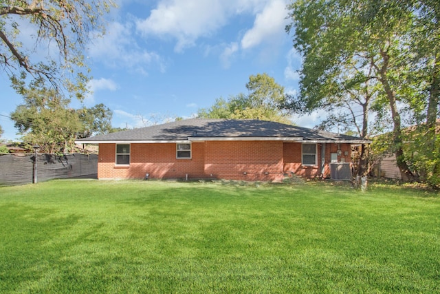 rear view of house with central air condition unit and a yard