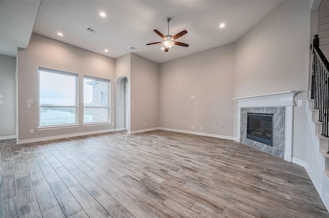 unfurnished living room featuring ceiling fan, light hardwood / wood-style floors, and a tiled fireplace