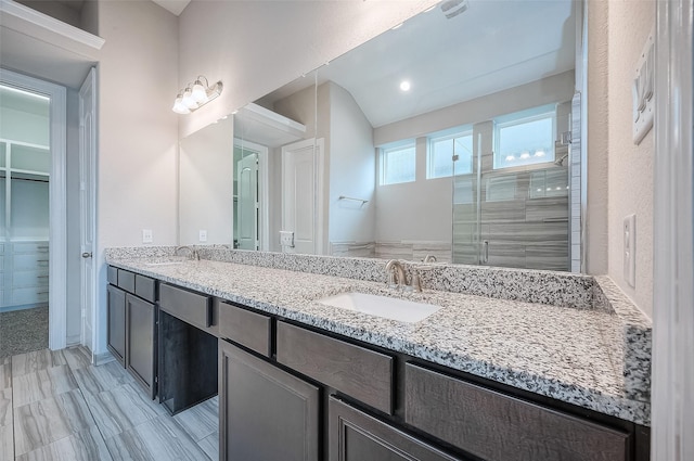 bathroom with vanity, a shower with door, and lofted ceiling