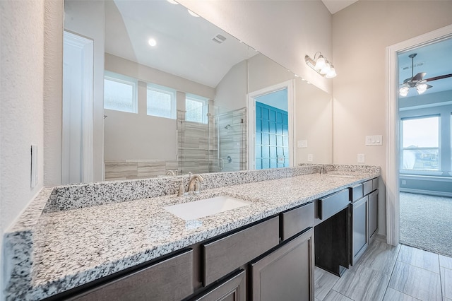 bathroom featuring ceiling fan, a shower with door, vanity, and vaulted ceiling