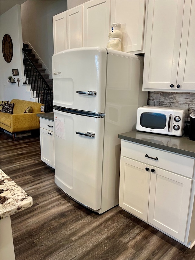 kitchen featuring decorative backsplash, white cabinetry, dark hardwood / wood-style flooring, and white appliances