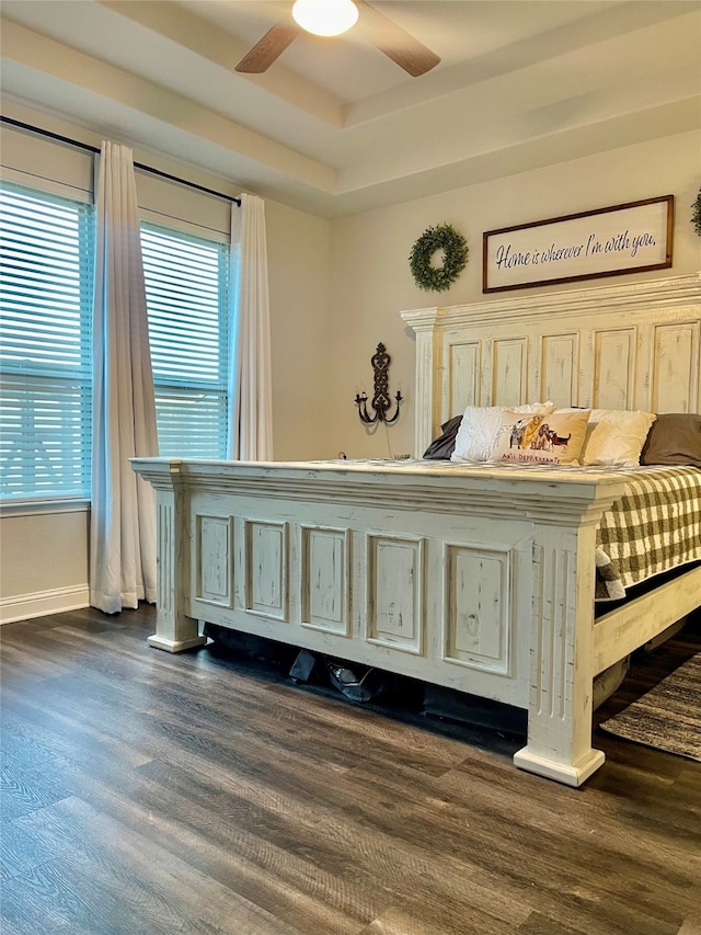 bedroom featuring ceiling fan, dark hardwood / wood-style flooring, and a tray ceiling