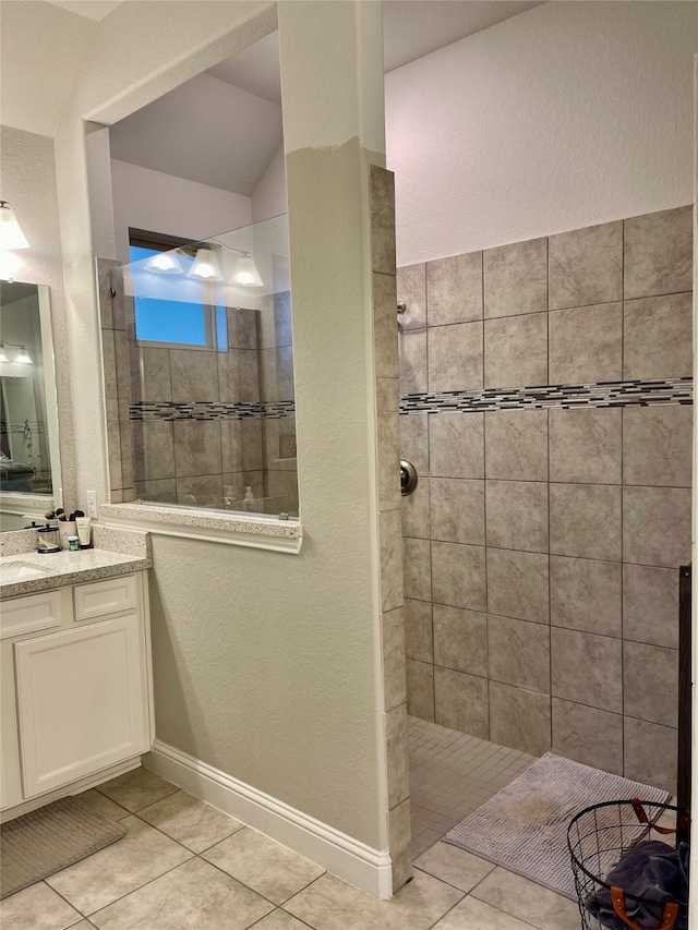 bathroom featuring a tile shower, vanity, and tile patterned floors