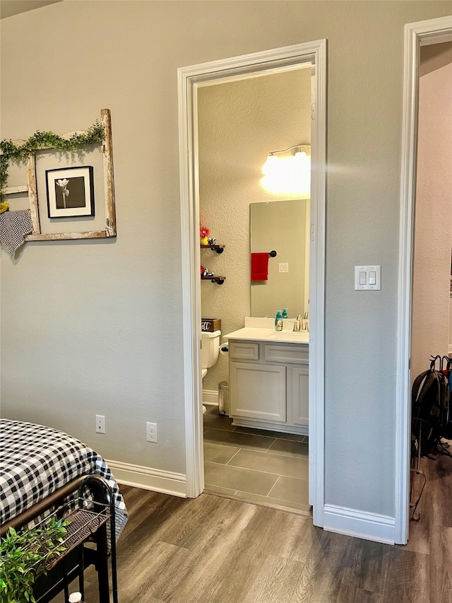 bedroom featuring ensuite bathroom, hardwood / wood-style floors, and sink