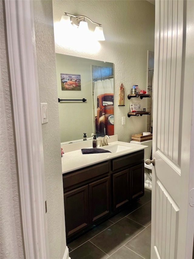 bathroom with toilet, vanity, and tile patterned floors