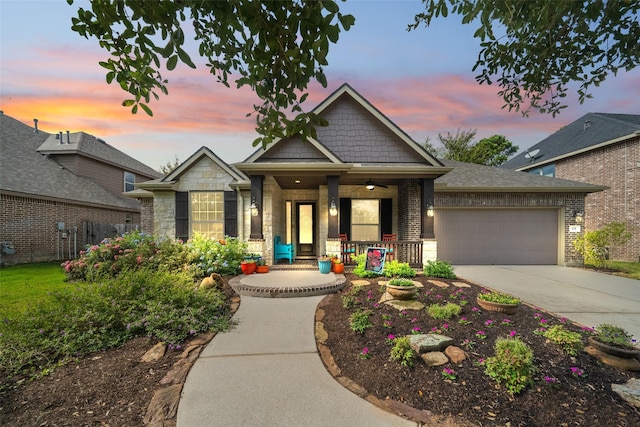 craftsman-style home with brick siding, a porch, concrete driveway, an attached garage, and stone siding