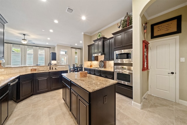 kitchen with stainless steel appliances, sink, crown molding, a kitchen island, and backsplash