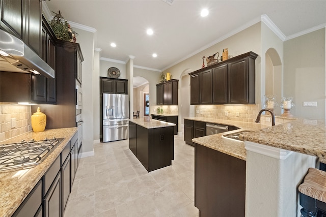 kitchen with appliances with stainless steel finishes, light stone counters, tasteful backsplash, and a kitchen island