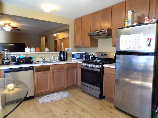 kitchen featuring light wood-type flooring, stainless steel appliances, ceiling fan, and sink