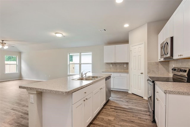 kitchen with white cabinets, appliances with stainless steel finishes, sink, and an island with sink