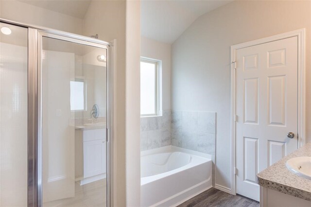 bathroom featuring lofted ceiling, hardwood / wood-style flooring, vanity, and a bath