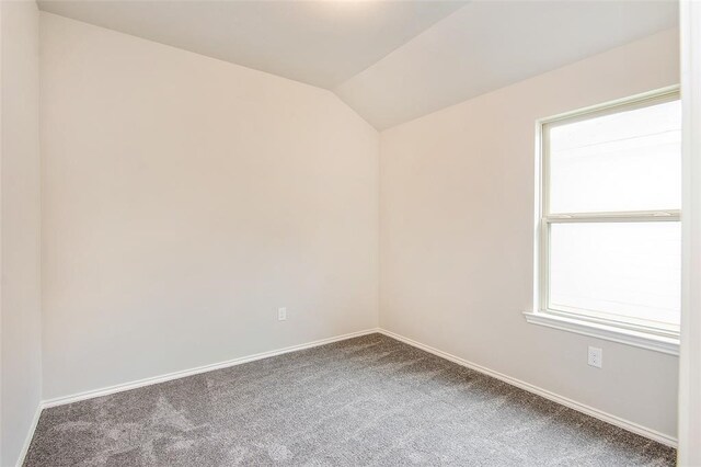 carpeted spare room with lofted ceiling