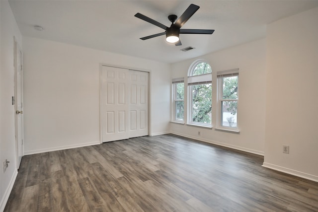 unfurnished bedroom with dark hardwood / wood-style flooring, ceiling fan, and a closet