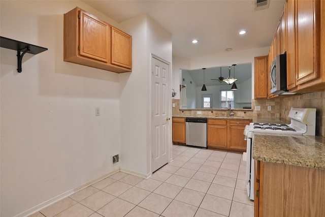 kitchen with sink, light tile patterned floors, light stone countertops, pendant lighting, and appliances with stainless steel finishes