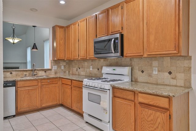 kitchen featuring stainless steel appliances, hanging light fixtures, sink, and light stone counters