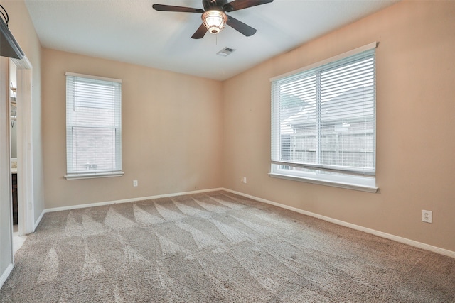 carpeted spare room featuring a wealth of natural light and ceiling fan