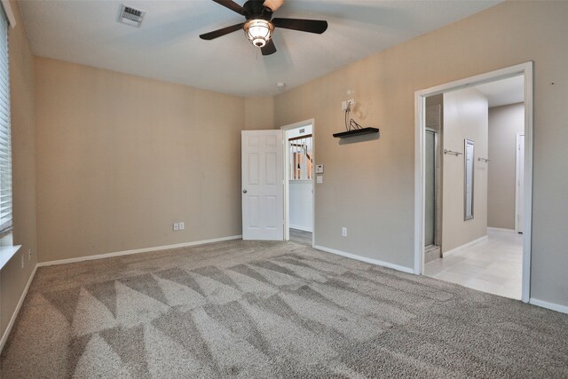 unfurnished bedroom with ensuite bathroom, light colored carpet, and ceiling fan