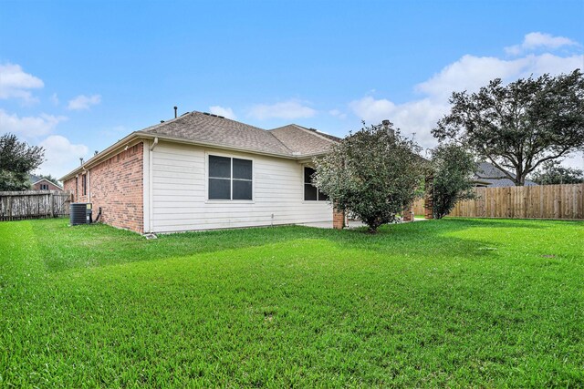 back of property featuring cooling unit and a lawn