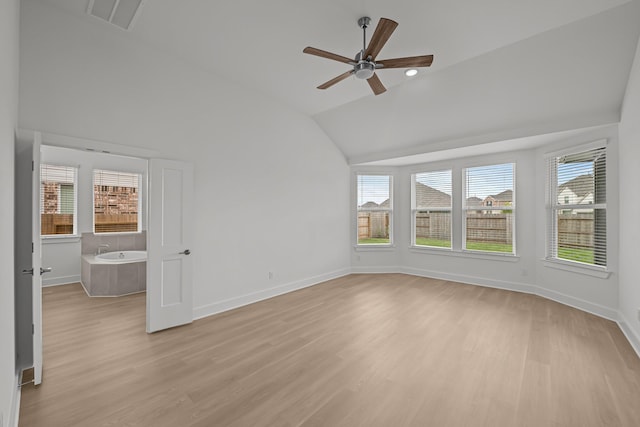 spare room featuring a ceiling fan, light wood-style floors, lofted ceiling, and plenty of natural light