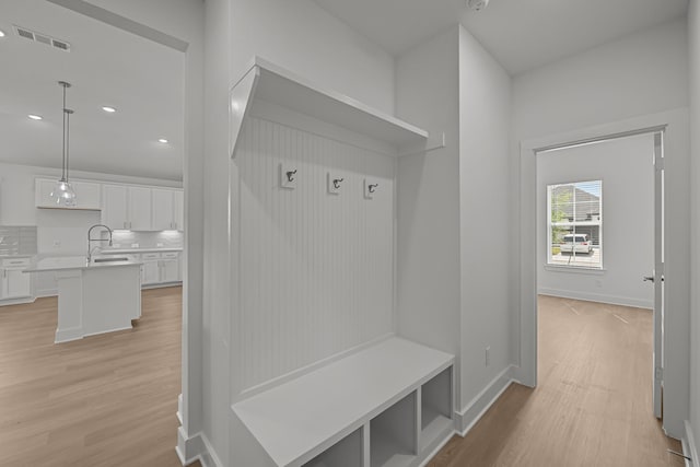 mudroom featuring baseboards, visible vents, light wood-style floors, and a sink