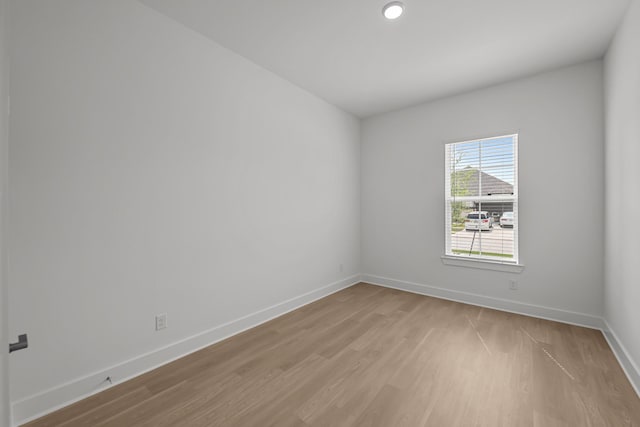 spare room with baseboards and light wood-type flooring
