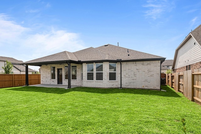 back of property with a fenced backyard, brick siding, a patio, roof with shingles, and a lawn