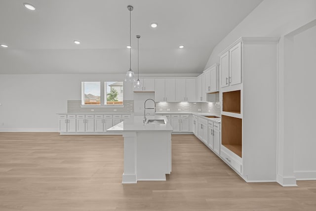 kitchen featuring a sink, tasteful backsplash, white cabinetry, vaulted ceiling, and light wood-style flooring