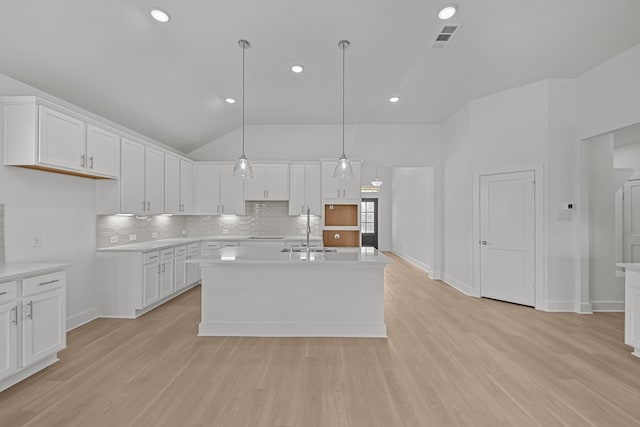 kitchen featuring tasteful backsplash, visible vents, light wood-style floors, and a sink
