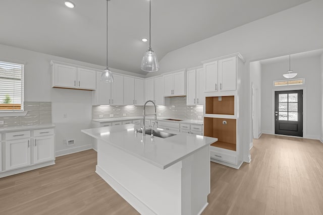 kitchen with a sink, white cabinets, an island with sink, and light wood-type flooring