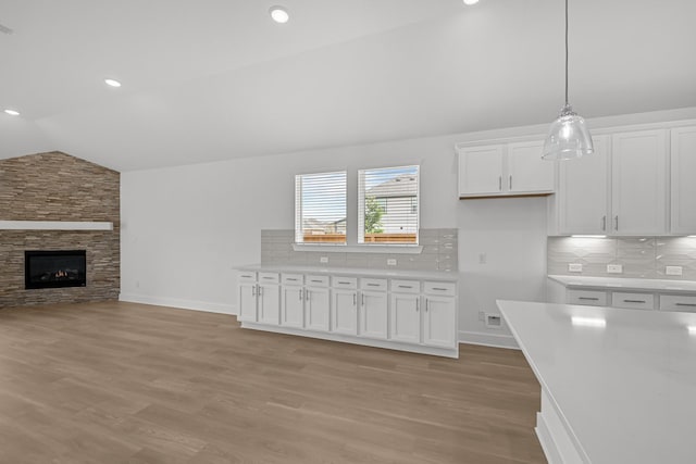 kitchen with backsplash, white cabinetry, lofted ceiling, and light countertops