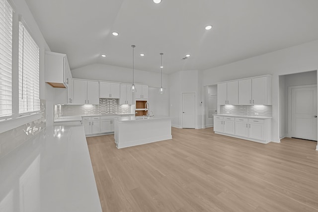 kitchen featuring recessed lighting, a sink, a center island with sink, tasteful backsplash, and light countertops