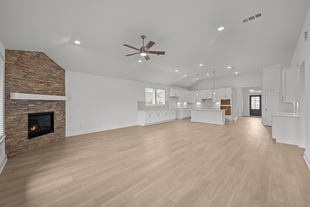 unfurnished living room with visible vents, ceiling fan, vaulted ceiling, and a healthy amount of sunlight