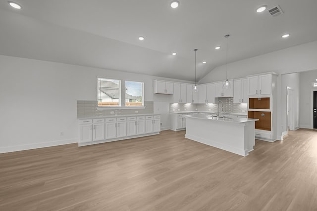 kitchen with white cabinets, decorative backsplash, lofted ceiling, and a sink