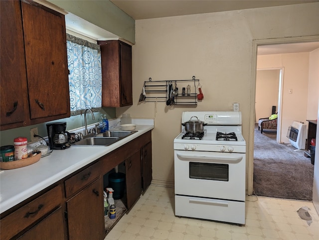 kitchen featuring light carpet, sink, heating unit, white range with gas stovetop, and dark brown cabinets