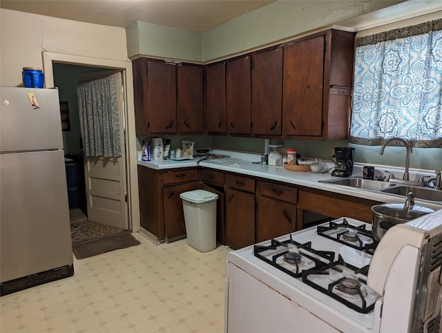 kitchen with white appliances, dark brown cabinets, and sink