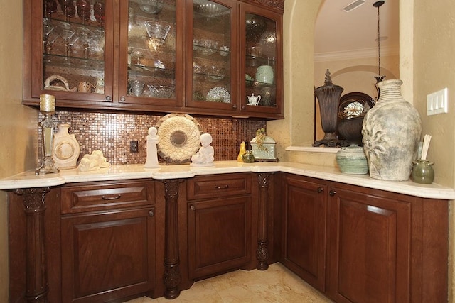 bar with ornamental molding, dark brown cabinetry, hanging light fixtures, and backsplash