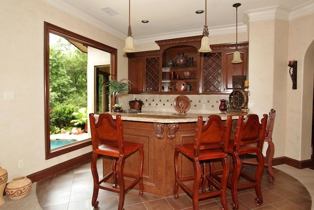 bar featuring ornamental molding, hanging light fixtures, dark tile patterned flooring, and tasteful backsplash