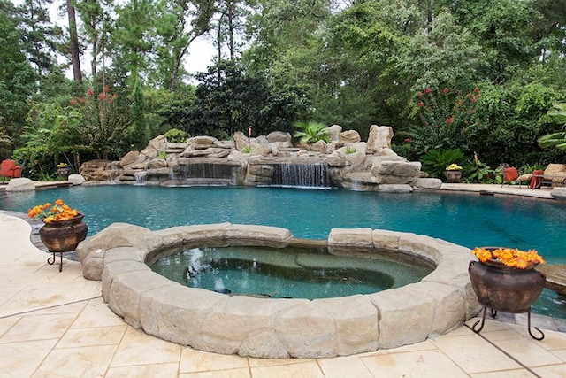 view of swimming pool with pool water feature and an in ground hot tub