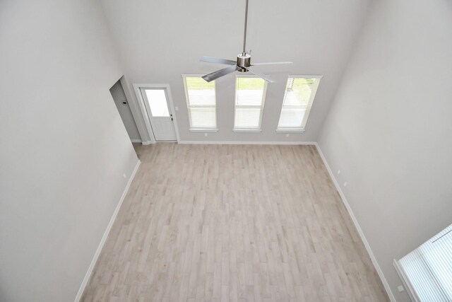 22126 Oceania Shores Dr, Hockley, TX 77447 - unfurnished living room featuring baseboards, a ceiling fan, light wood-type flooring, and a high ceiling