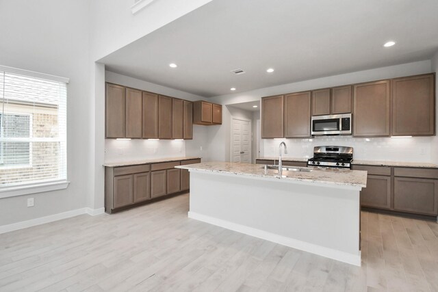 22126 Oceania Shores Dr, Hockley, TX 77447 - kitchen with appliances with stainless steel finishes, a sink, tasteful backsplash, light wood-style floors, and light stone counters