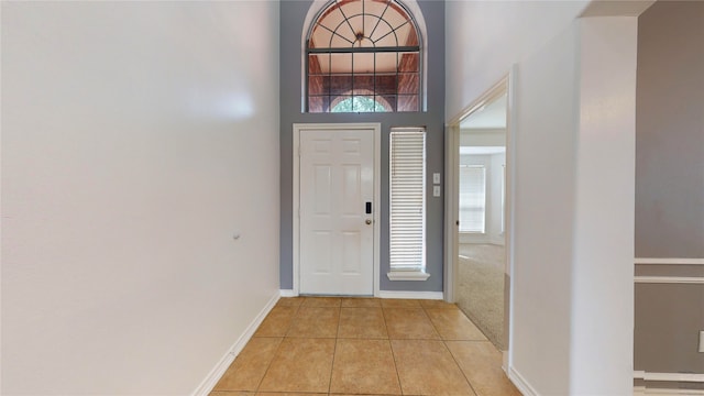 foyer entrance with a high ceiling, a healthy amount of sunlight, and light tile patterned flooring