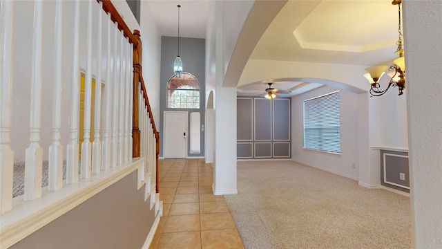 carpeted entrance foyer with ceiling fan and a tray ceiling