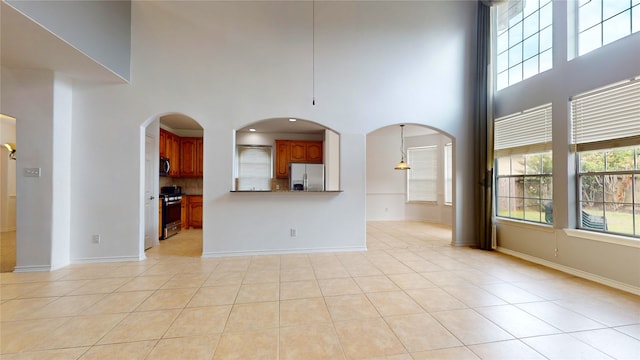 unfurnished living room featuring light tile patterned floors and a towering ceiling