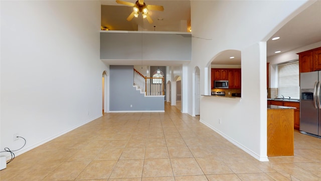 unfurnished living room featuring a high ceiling, light tile patterned flooring, and ceiling fan