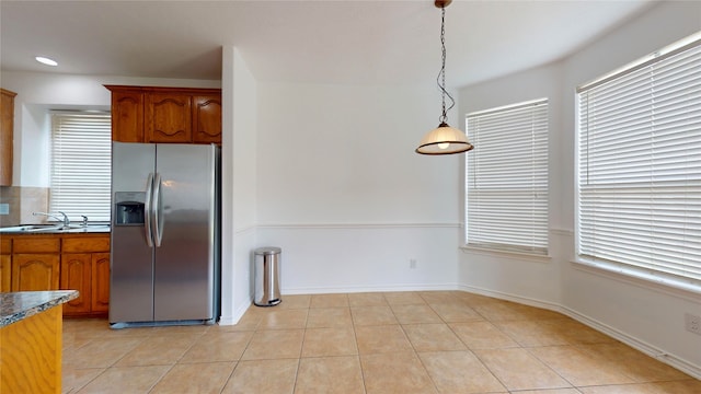 kitchen with pendant lighting, stainless steel refrigerator with ice dispenser, sink, and light tile patterned flooring